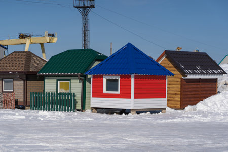 Small beautiful houses for demonstration of varieties of metal siding and metal tiles. Winter