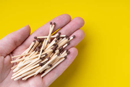 Heap of wooden matchstick in a female palm on a yellow backgroundの写真素材