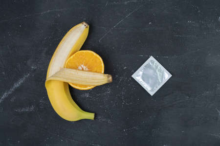 yellow banana hugs orange, condom nearby. Penis and vagina symbol.