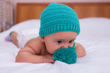 Newborn baby in a green hat is played with a buboの写真素材