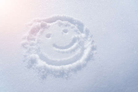 Drawing of a smiley in the snow, a ray of light. Top viewの写真素材