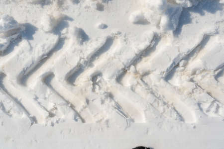 Tractor wheel imprint on white snow, transport trail