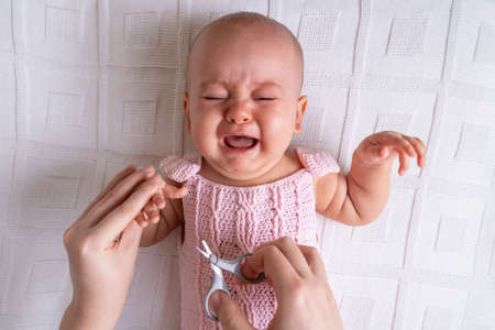 Crying newborn baby cries while cutting nails, horizontal photoの写真素材
