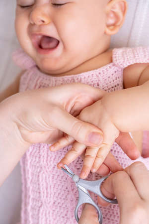 Newborn baby cries during nail clipping on handの写真素材