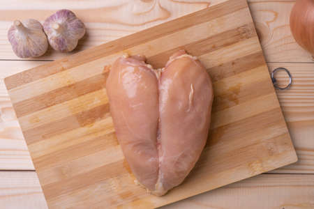 Raw skinless chicken breast on a cutting board.の写真素材
