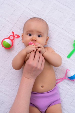 Funny newborn took the pacifier from mom's hands and looks at the cameraの写真素材