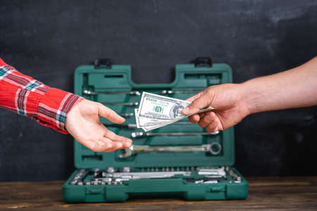 The concept of buying a car as a gift, a man's hand with dollars gives money to the sellerの写真素材