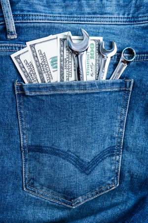 wrenches and dollar bills in the back pocket of blue jeans, vertical fotoの写真素材