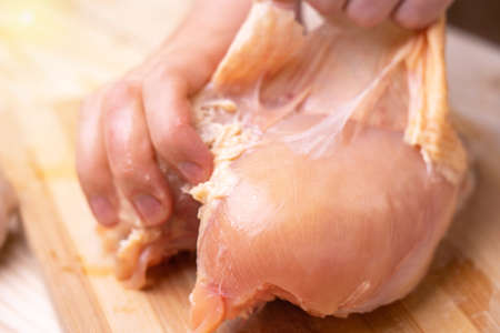 Chef's hands peeling raw chicken breast. Close upの写真素材