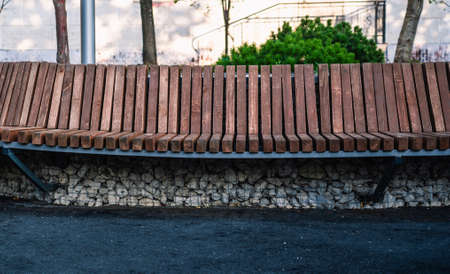 Curved wooden bench in a city park, black soft rubber coating on the bottomの写真素材