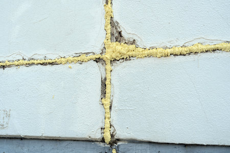 The wall of a panel house is in the process of repair and insulation. The joints between the plates are filled with mounting foamの写真素材