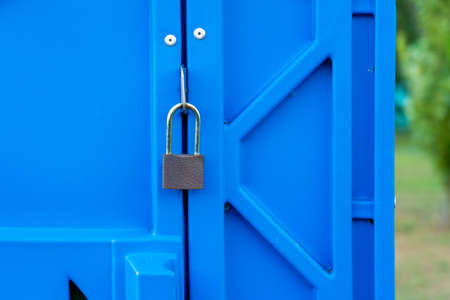 Padlock on the door of the public blue toilet cubicle