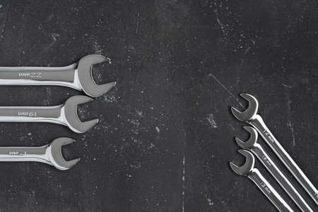 Different size wrenches on black background with copy space, steel hand working tools