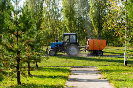 Orange vacuum sweeper, towed by a blue tractor, works on street cleaning : September 20, 2021...