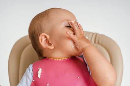 The baby sitting on a chair during feeding made a facepalm gestureの写真素材