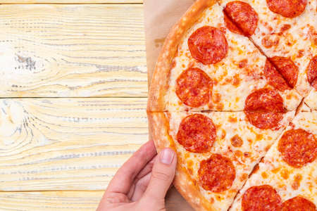 A woman's hand takes a piece of pepperoni pizza, copy spaceの写真素材