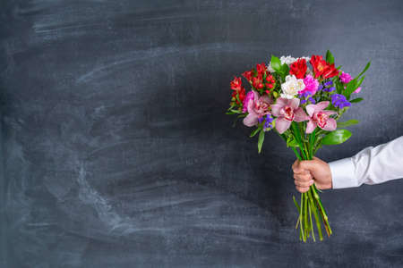 A man holding a beautiful bouquet of flowers on the background of a chalk boardの写真素材