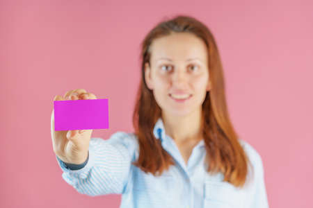 Smiling businessman woman holding pink empty business card, selective focusの写真素材