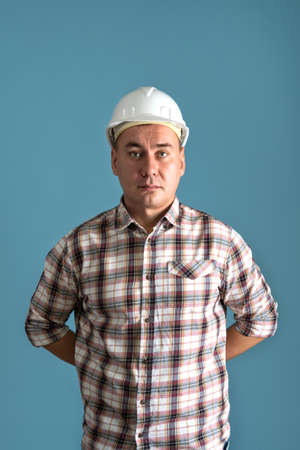 A construction worker in a shirt and a white helmet on a blue backgroundの写真素材