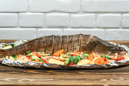 Fresh raw fish pike perch on foil for baking with vegetables, prepared for cooking, close-upの写真素材