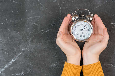 Alarm clock in women's hands, copy space. The concept of time managementの写真素材