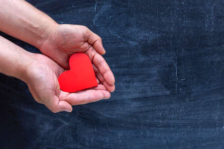 man holding red heart in hands. chalk Board backgroundの写真素材