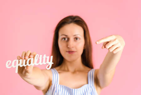 The concept of equality. The woman holds the word EQUALITY at arm's length and points at it with her index fingerの写真素材