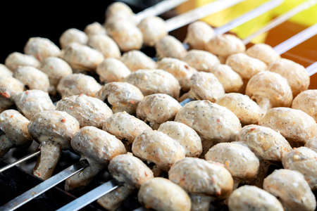 Fresh Mushrooms champignons on metal skewers are cooked on charcoalの写真素材