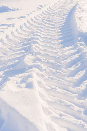 Traces of tractor wheels in the snow. The imprint of the tread of municipal services equipment during snow clearing. Vertical fotoの写真素材