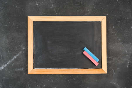 An empty black chalk board in a frame and red and blue chalk next to it, top viewの写真素材