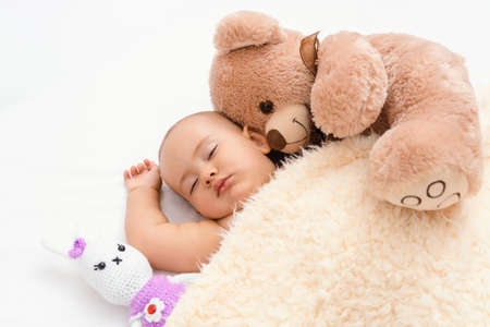 Daytime sleep time in children. A newborn sleeps with his favorite toys under a blanket.の写真素材