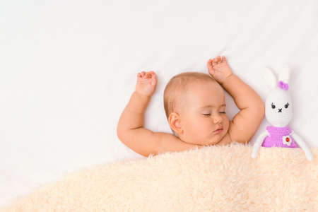 A newborn baby sleeps under a blanket with his favorite toy - a knitted hare. Copy spaceの写真素材