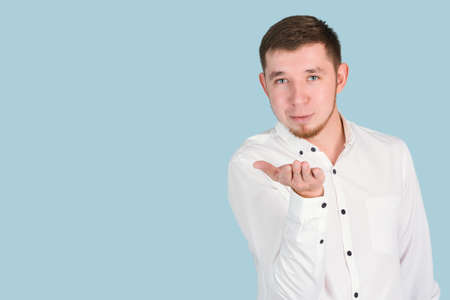 Bearded man blows a kiss blowing on the palm of his hand standing on a blue background, copyspaceの写真素材