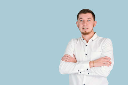 A confident bearded man stands with his arms crossed on a blue background, copyspaceの写真素材