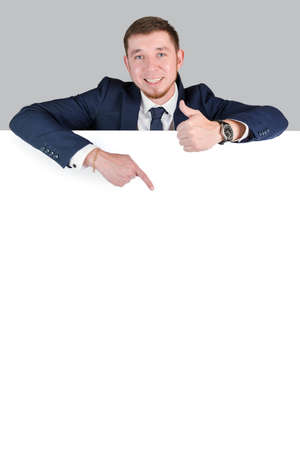 The businessman points with his index finger at the white blank board. vertical photoの写真素材