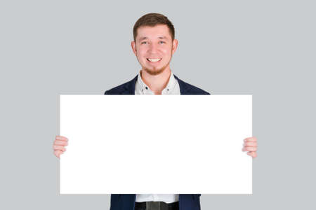 A businessman holds a rectangular white blank board with a place for text in his hands