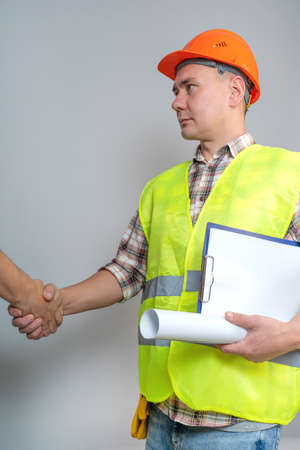 Architect-contractor, builder, worker, shakes hands with a client on a gray background.の写真素材