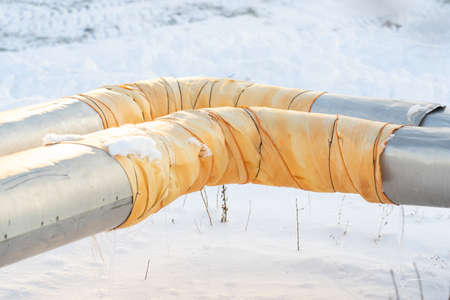 Central heating pipes sheathed with aluminum sheets. The corner element of the pipe is wrapped with a repair patch made of yellow insulating material. close upの写真素材