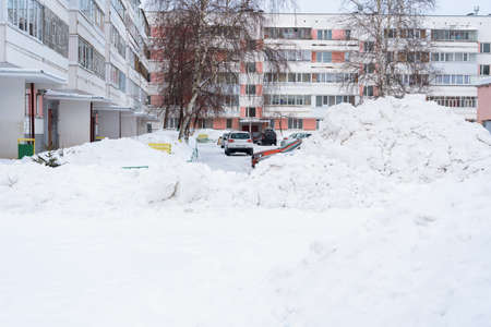 Snow cleaning in Russia. A huge pile of snow in the courtyard of an apartment buildingの写真素材
