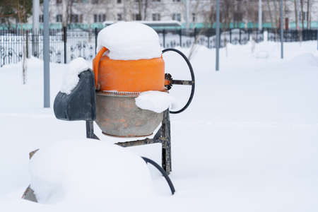 Electric concrete mixer under the snow yf abandoned construction site in Russia.の写真素材