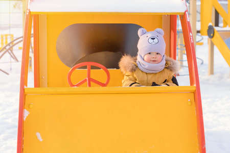 A kid 15-25 months old driving a toy car on a children's playgroundの写真素材