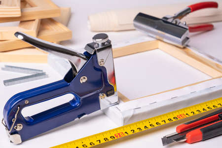 The process of stretching a canvas with a photo printed on it onto a wooden stretcher. The canvas stretching tool is a stapler gun, forceps, a roll of canvas ruler and a knife.の写真素材
