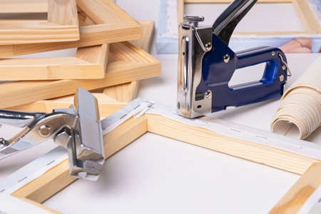 The process of stretching a canvas with a photo printed on it onto a wooden stretcher. A tool for stretching the canvas nearby.の写真素材