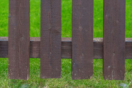 Brown wooden fence close-up, green lawn at the backの写真素材