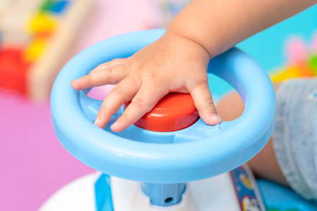 The kid presses the red signal button located on the steering wheel of the toy car, close-upの写真素材