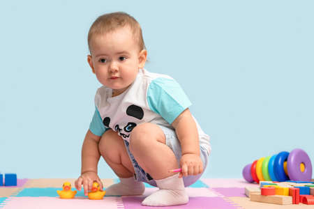 Toddler in the playroom playing with yellow rubber ducklings for swimming.の写真素材