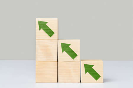 The concept of growth. Wooden cubes arranged in the form of stairs and pyramids with green arrows...