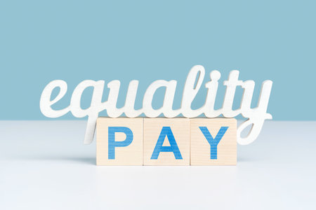The concept of equal pay, the word equality stands on three wooden cubes with the inscription pay. close-upの写真素材