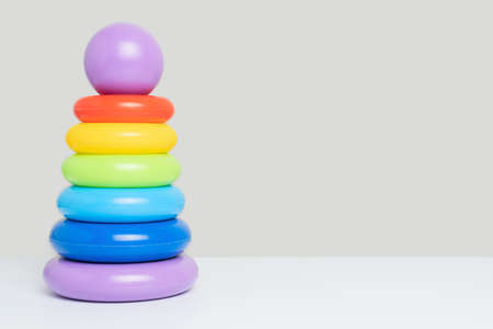 Children's educational toy pyramid of multicolored plastic rings on a gray background, copy spaceの写真素材