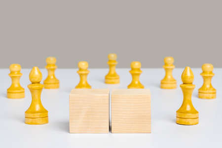 Two wooden cubes with space for text and chess pieces in the background.の写真素材